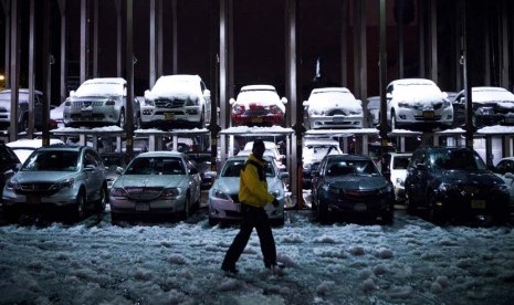 Seorang petugas parkir berjalan melewati mobil yang tertutup salju setelah diterpa badai Nor'easter di New York, Rabu (8/11). (Reuters/Andrew Burton)