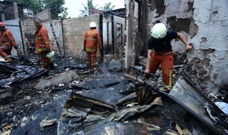 Seorang petugas pemadam kebakaran berusaha memindahkan motor yang hangus diantara puing rumah yang terbakar di Jalan Sodong Raya Timur 3, Jakarta Timur, Selasa (10/3). (Republika/Raisan Al Farisi)