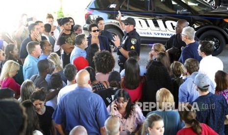 Seorang petugas polisi mengatakan kepada orang tua yang menunggu di Coral Springs Drive dan Sawgrass Expressway untuk pergi ke hotel Marriott untuk bertemu dengan anak-anak mereka menyusul penembakan di Marjory Stoneman Douglas High School di Parkland, Florida, Rabu, (14/2). 