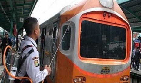  Seorang petugas PT. Kereta Api Indonesia ( PT. KAI), mengenakan alat penyemprot penumpang yang duduk di atas gerbong saat uji coba, di Stasiun Manggarai, Jakarta