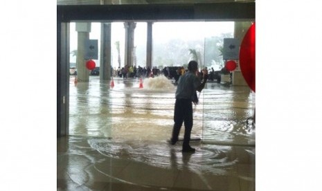 Seorang petugas sedang membersihkan lantai Terminal 3 Bandara Soekarno-Hatta yang digenangi air, Ahad (14/8).