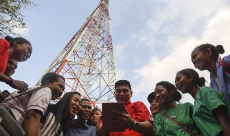 Seorang petugas Telkomsel bersama pemudi Alor mencoba layanan data pada selular di dekat base transceiver station (BTS),