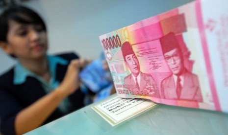 Pendapat Ulama Kontemporer Soal Bank Konvensional. Foto: Seorang petugas teller menghitung mata uang rupiah.    (ilustrasi)