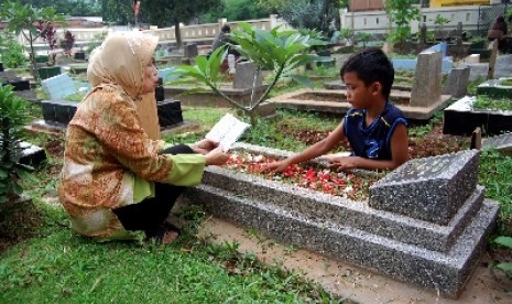 Seorang peziarah berdoa di depan makam sanak saudaranya di kompleks pemakaman Pejaten Barat, Jakarta Selatan.