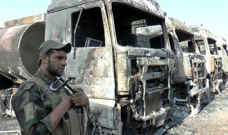 Seorang polisi Irak berdiri di sisi truk-truk yang terbakar di lokasi serangan bom bunuh diri di sebuah stasiun pembangkit di Kota Samara, sekitar 120 km sebelah utara Baghdad, Irak, pada 2 September 2017.  