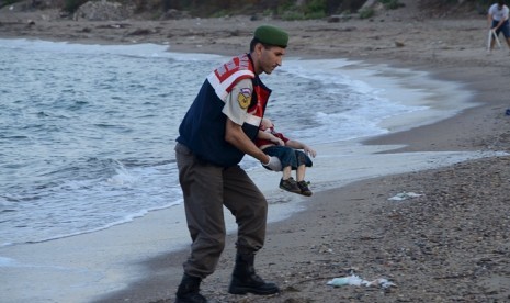 Seorang polisi membawa tubuh anak pengungsi Suriah, Alan Kurdi yang tenggelam di laut antara Turki menuju Yunani