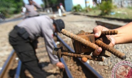 Seorang polisi memperlihatkan mur dan baut yang copot 