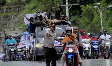 Seorang polisi mengarahkan massa pendukung Gubernur Papua Lukas Enembe dalam unjuk rasa menolak penetapan tersangka Gubernur Papua Lukas Enembe oleh Komisi Pemberantasan Korupsi (KPK) di Titik Nol, Taman Imbi, Kota Jayapura, Papua, Selasa (20/9/2022). Polri mengerahkan sekitar 2.000 personel dalam mengamankan aksi dukungan kepada Lukas Enembe yang ditetapkan oleh KPK sebagai tersangka gratifikasi tersebut. 