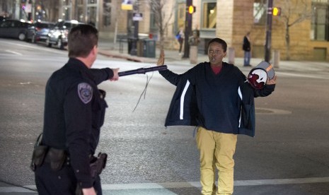 Ilustrasi - Seorang polisi menghentikan bocah laki-laki saat berjalan dari kerumunan massa, Salt Lake, Amerika.