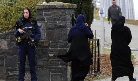 Seorang polisi perempuan dengan bunga mawar berjaga di pemakaman korban penembakan di Memorial Park Cemetery, Christchurch, Selandia Baru, Kamis (21/3).