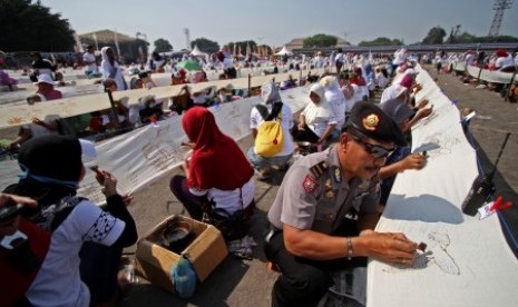 Seorang polisi tampak ikut berpartisipasi dalam kegiatan membatik kain terpanjang di dunia yang berlangsung di Yogyakarta, Kamis (2/10).