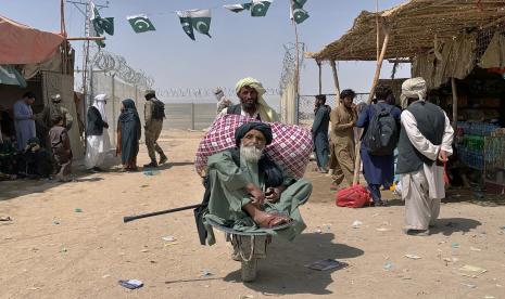 Seorang portir mendorong gerobak yang membawa seorang pria tua Afghanistan saat ia memasuki Pakistan melalui titik penyeberangan perbatasan, di Chaman, Pakistan, Jumat, 20 Agustus 2021. Sejumlah negara dunia, termasuk Kanada, membantu proses pengungsian warga Afghanistan.