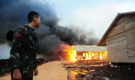 Seorang prajurit TNI menyaksikan permukiman eks-Gafatar yang dibakar massa di kawasan Monton Panjang, Dusun Pangsuma, Desa Antibar, Mempawah Timur, Kabupaten Mempawah, Kalbar, Selasa (19/1). (Antara/Jessica Helena Wuysang)