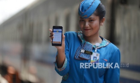 Seorang pramugari menunjukan aplikasi untuk memesan tiket kereta api online di dalam gerbong kereta Jayabaya tujuan Malang di Stasiun Pasar Senen, Jakarta, Ahad (19/3). 