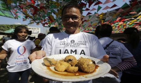 Seorang pria asal Filipina membawa sepiring balut. 