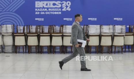 Seorang pria berjalan di depan logo KTT BRICS 2024 di gedung Kazan Expo di Kazan, Rusia, 21 Oktober 2024. Rusia mengatakan bahwa setiap upaya AS untuk memaksa negara-negara menggunakan dolar AS akan menjadi bumerang jika mereka menciptakan mata uang mereka sendiri. 