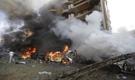  Seorang pria berjalan di depan mobil yang terbakar di lokasi ledakan bom dekat Kedutaan Besar Iran  di Beirut, Lebanon, Selasa (19/11).   (AP/Hussein Malla) 