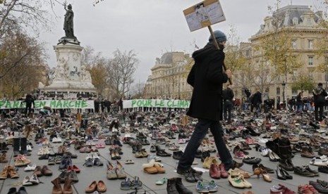 Seorang pria berjalan di tengah ribuan pasang sepatu sebagai bentuk protes perubahan iklim di Paris, Prancis.