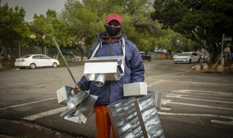 Seorang pria bertopeng yang menjual kerajinan logam buatan tangan berjalan melalui jalan-jalan di kota pedesaan Parys, Afrika Selatan, 26 November 2021. Departemen Kesehatan Afrika Selatan dan ilmuwan dari Network for Genomic Surveillance mengungkapkan rincian Covid yang baru terdeteksi dan sangat bermutasi -19 varian, B.1.1.529.