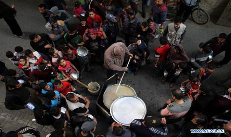 Seorang pria Gaza, Walid al-Hattab, memasak sup tradisional Palestina, garisha, dalam mangkuk besar untuk memberi makan keluarga miskin di lingkungannya selama Ramadhan. Ramadhan tahun ini adalah tahun keenam Walid al-Hattab berturut-turut memasak untuk keluarga miskin.  Koki Bagi Warga Miskin, Walid Memasak Sup Gratis di Jalanan Gaza