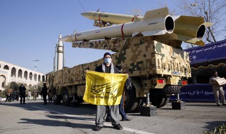 Seorang pria Iran memegang bendera anti-AS sambil berdiri di dekat rudal Zolfaghar-Basir dan Dezful yang ditampilkan di Masjid Mosallah pada kesempatan ulang tahun kedua serangan rudal Iran ke pangkalan udara militer AS Ayn al-Asad di Irak setelah pembunuhan pemimpin Iran. komandan Qasem Soleimani, di Teheran, Iran, 07 Januari 2022.