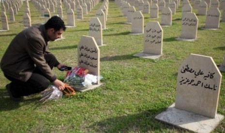 Seorang pria meletakkan bunga di salah satu makam korban serangan gas beracun di Halabja, Irak pada 16 Maret 1988.