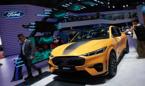 Seorang pria melewati mobil Mustang MACH-E yang dipajang di stan perusahaan Ford, pada hari pers pertama Pameran Industri Otomotif Internasional Shanghai ke-20, di Shanghai, Tiongkok, 18 April 2023. Ford Motor Co memotong harga kendaraan listrik Mustang Mach-E dan membuka kembali pesanan.