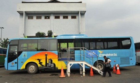 Seorang pria melintas disamping bus Transjakarta, APTB (Angkutan Perbatasan Terintegrasi Busway) di halte transjakarta di terminal Bekasi, Minggu (22/4). Setelah sempat berhenti beroperasi sejak diresmikan beberapa waktu lalu akibat protes awak angkutan mi