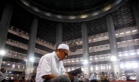 Seorang pria membaca kiab suci Al-Qur'an usai melaksanakan ibadah Shalat Dzuhur di Masjid Istiqlal, Jakarta, Senin (23/7). (Agung Supriyanto/Republika)