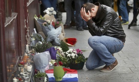 Seorang pria memberikan penghormatan di luar restoran Le Carillon pagi hari setelah serangkaian serangan mematikan di Paris, 14 November 2015.