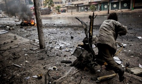 Seorang pria membersihkan pecahan truk yang hancur dihantam roket di sebuah jalan di Distrik Aleppo, Suriah.