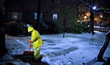  Seorang pria membersihkan salju yang disebabkan oleh badai Nor'easter di kawasan Kota Stuyvesant, New York, Rabu (8/11). (Reuters/Andrew Burton) 