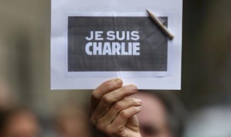 Seorang pria memegang pensil dan kartu sebagai bentuk penghormatan terhadap korban tewas di kantor Charlie Hebdo. 