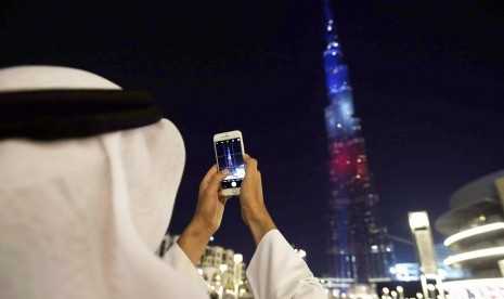 Seorang pria mengambil foto bangunan ikonik Dubai Burj Khalifa.