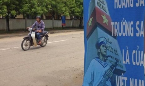 Seorang pria mengendarai sepeda motor melewati poster yang menegaskan kedaulatan Vietnam di Laut Cina Selatan di Pulau Phu Quoc pada 11 September 2014.