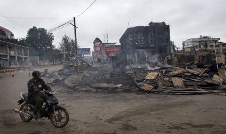  Seorang pria mengendarai sepeda motor melintasi bangunan yang terbakar yang menampung sebuah panti asuhan untuk anak-anak Muslim di Lashio, Myanmar, Kamis (30/5).     (AP/Gemunu Amarasinghe)