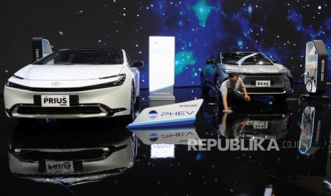 Seorang pria mengepel lantai di dekat Toyota Prius PHEV dan Toyota BZ4X selama Pameran Otomotif Internasional Indonesia di Tangerang, Indonesia, 18 Juli 2024.