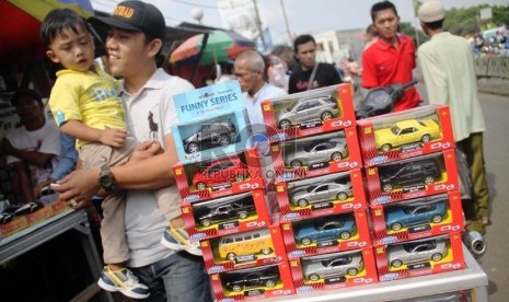  Seorang pria menggendong anaknya saat berbelanja mainan anak di Pasar Gembrong, Jatinegara, Jakarta Timur, Jumat (9/8).  (Republika/ Yasin Habibi)