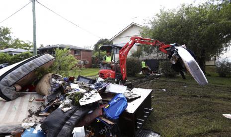 Seorang pria menggunakan ekskavator mengumpulkan puing-puing yang rusak akibat air banjir di Lismore, Australia, Rabu (2/3/2022). Air bergerak ke selatan ke New South Wales dari negara bagian Queensland, menjadi bencana terburuk di kawasan itu.