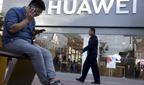 Seorang pria menggunakan ponselnya di depan toko Huawei di Beijing, Cina, Senin (20/5). 