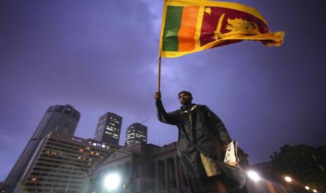 Seorang pria mengibarkan bendera nasional Sri Lanka saat dia berdiri di barikade yang menghalangi pintu masuk ke kantor presiden selama protes di Kolombo, Sri Lanka, Senin, 11 April 2022. Ribuan warga Sri Lanka memprotes menyerukan presiden negara itu Gotabaya Rajapaksa untuk mengundurkan diri di tengah krisis ekonomi terburuk dalam sejarah.