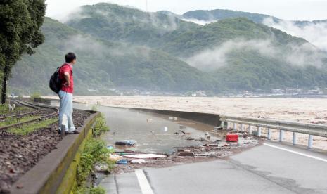 Seorang pria menyaksikan Sungai Kuma di Prefektur Kumamoto meluap, Sabtu (4/7). Sekitar 75 ribu orang diminta untuk mengungsi di Jepang barat karena hujan deras. 