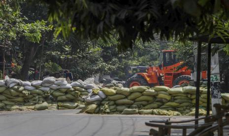 Seorang pria menyaksikan tentara menggunakan buldoser untuk menghilangkan barikade karung pasir yang dipasang oleh pengunjuk rasa anti-kudeta untuk melindungi mereka dari pasukan keamanan di Mandalay, Myanmar, Kamis, 18 Maret 2021.