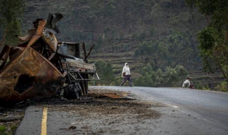 Seorang pria menyeberang di dekat truk yang hancur di jalan menuju kota Abi Adi, di wilayah Tigray di Ethiopia utara pada 11 Mei 2021. Seorang juru bicara otoritas Tigrayan mengatakan Selasa, 20 September 2022 bahwa Eritrea telah meluncurkan serangan penuh. skala ofensif di sepanjang perbatasan negara dengan Ethiopia utara.