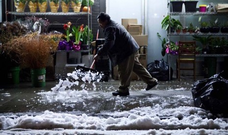  Seorang pria menyingkirkan salju yang disebabkan oleh badai Nor'easter di kawasan Lower East Side di New York, Rabu (8/11). (Reuters/Andrew Burton) 