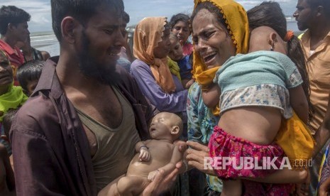  Seorang pria Muslim Rohingya Naseer Ud Din memegang anak laki-lakinya, Abdul Masood, yang tenggelam saat kapal yang mereka tumpangi terbalik sebelum mencapai pantai, saat istrinya Hanida Begum menangis saat mencapai pantai Teluk Benggala di Shah Porir Dwip, Bangladesh, Kamis, (14/9).