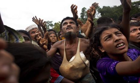 Seorang pria Rohingya mengulurkan tangannya untuk mendapatkan makanan yang dibagikan oleh sukarelawan lokal, dengan kantong beras kembung yang dimasukkan ke dalam rompinya di Kutupalong, Bangladesh, 9 September 2017. Perdana Menteri Bangladesh mengatakan Senin bahwa masa tinggal yang berkepanjangan lebih dari 1 juta Pengungsi Rohingya di kamp-kamp yang padat di negara itu telah menjadi masalah keamanan dan stabilitas.