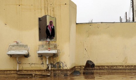 Seorang pria Saudi terlihat dalam cermin di rumahnya yang terendam banjir setelah hujan lebat di Tabuk,Arab Saudi, Senin (28/1).   (Reuters/Mohamed Alhwaity)