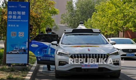 Seorang pria yang memakai masker  masuk ke dalam Baidu Apollo Robotaxi di titik penjemputan penumpang di Shougang Park di Beijing (ilustrasi).