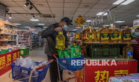 Seorang pria yang mengenakan masker pelindung memegang botol berisi minyak goreng